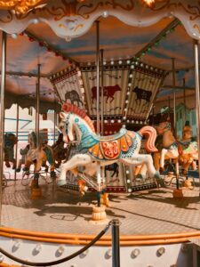 A vibrant carousel with ornate horses at a theme park in Thailand during daylight.